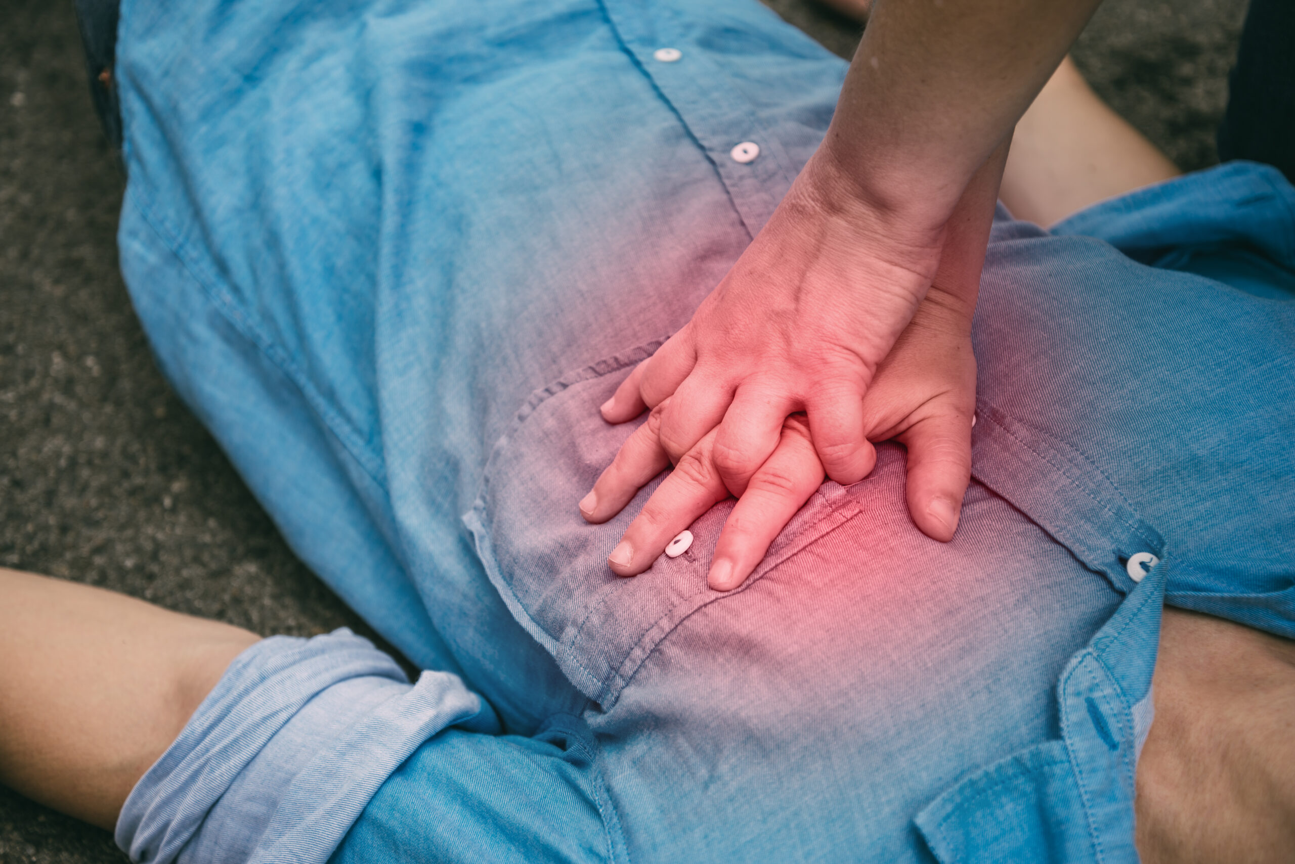 Close up of hands administering CPR on a chest that is glowing in the heart area, indicating cardiac arrest