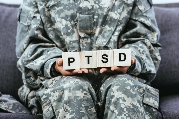 Cropped image of military service member holding PTSD block letters